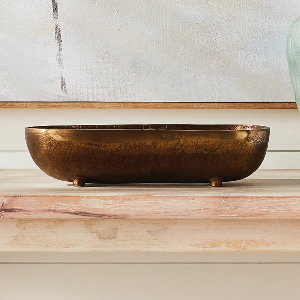 Small antique brass narrow decorative bowl styled on console table creating a refined linear accent in modern organic interior