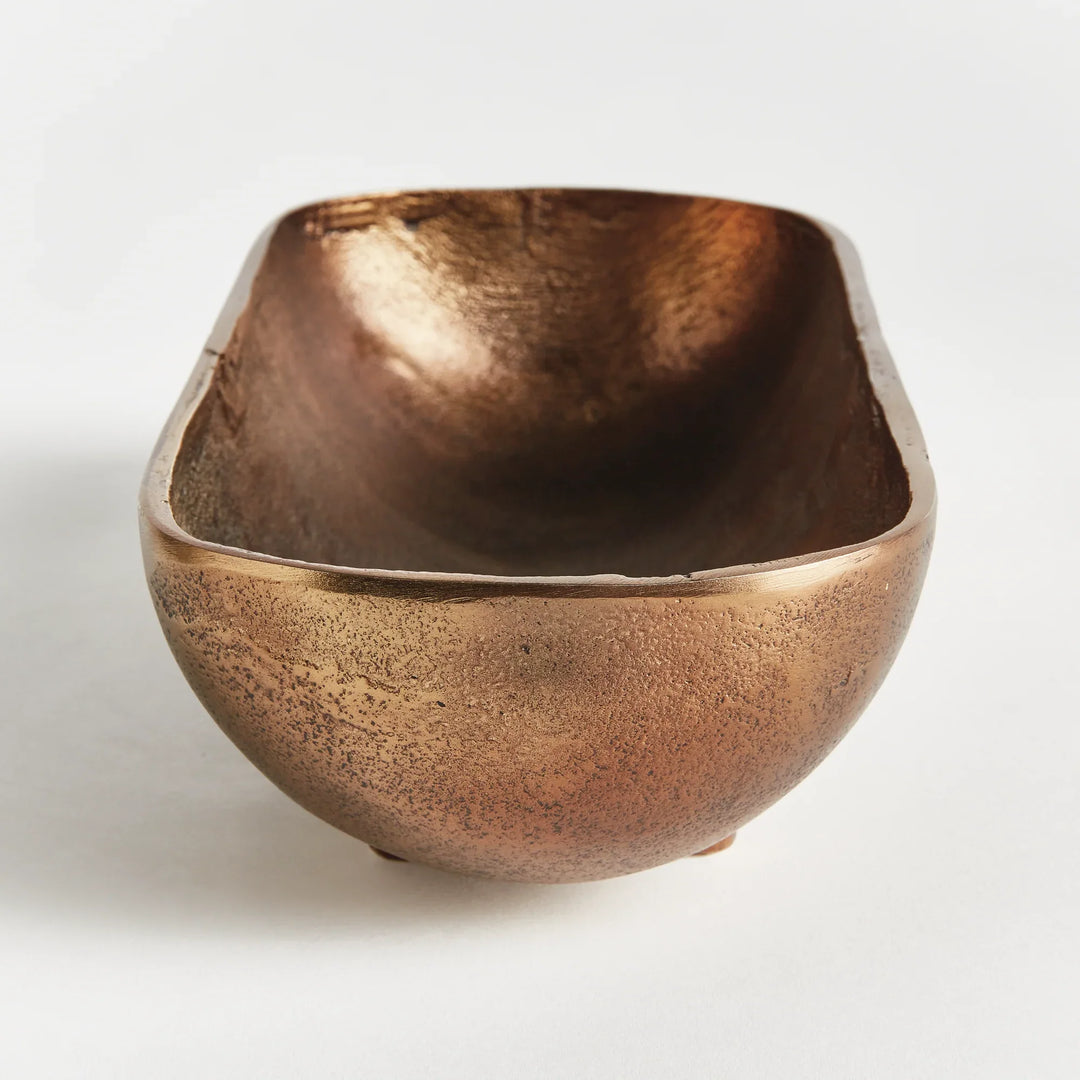 Small narrow decorative bowl in antique brass cast aluminum showing sculpted interior and warm metallic finish modern organic