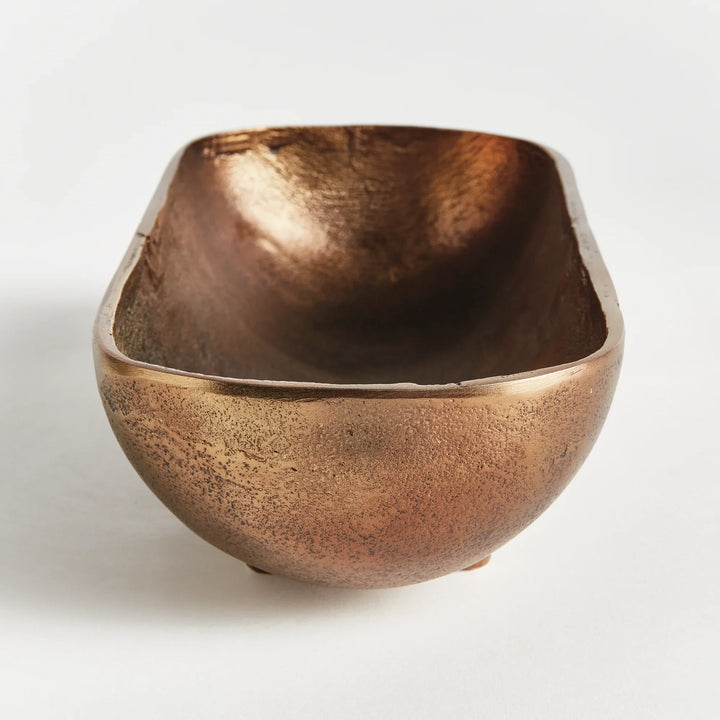 Small narrow decorative bowl in antique brass cast aluminum showing sculpted interior and warm metallic finish modern organic