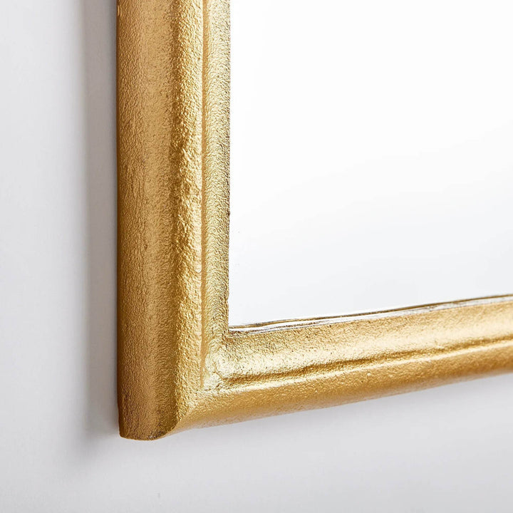 Corner detail of arched mirror; textured gold aluminum frame and clear glass show crisp build and clean lines – Transitional.