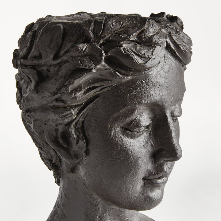 View of an antique black bust planter, showing sculpted hair, facial features and textured concrete finish. Transitional