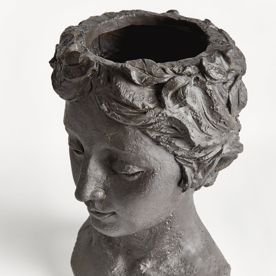 Angled close view of a female bust planter, showing the top planting opening and antique black textured surface. Transitional