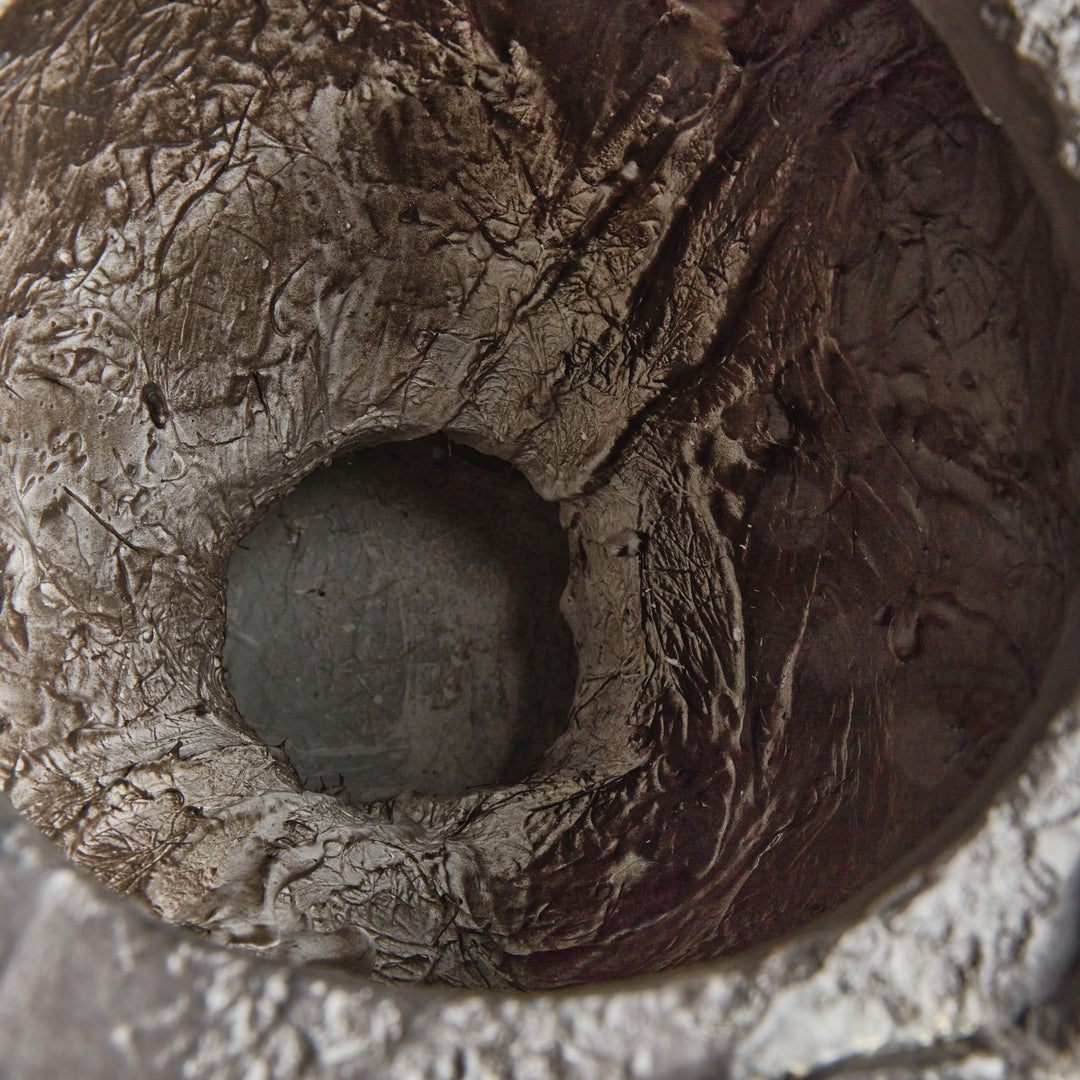 Interior detail of a concrete composite bust planter, showing the drainage plug in the textured planting cavity. Transitional