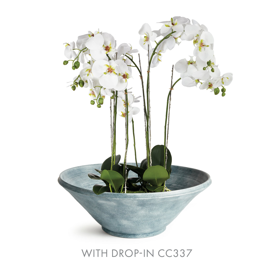Aveline washed blue terracotta bowl holding a white orchid bowl drop-in and leaves against a white background. Modern Organic
