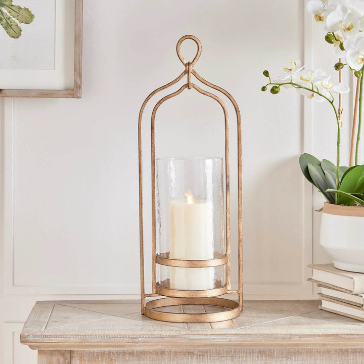 Crafted with precision from cast aluminum and embellished with hammered glass, the Amara Gold Hurricane Large effortlessly blends form and function. Expertly designed for transitional and modern settings, it boasts a decorative yet practical loop handle for easy movement and use. A must-have addition to any home, this hurricane exudes elegance and versatility with its top-quality materials and stylish details.