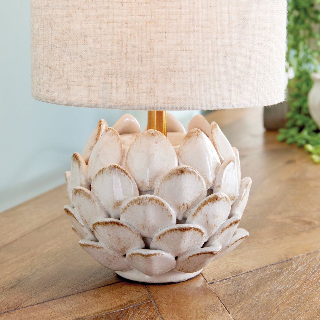 Transform your space with this exquisite ceramic table lamp, inspired by the intricate beauty of artichokes. Hand-finished with antique edges, it exudes a timeless elegance. Complete with a natural linen shade, this lamp is the perfect addition to any sophisticated and exclusive setting.