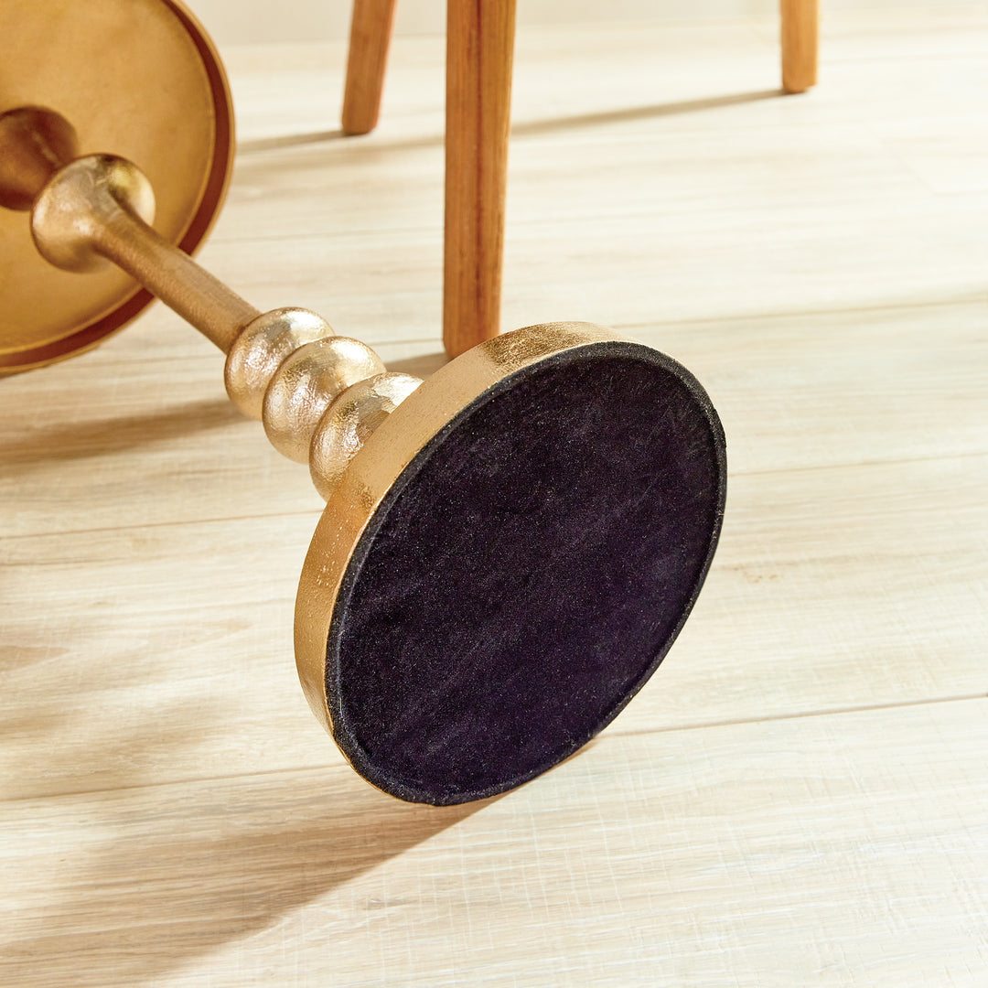 Underside of glam accent table showing round velvet base pad and turned brass stem.