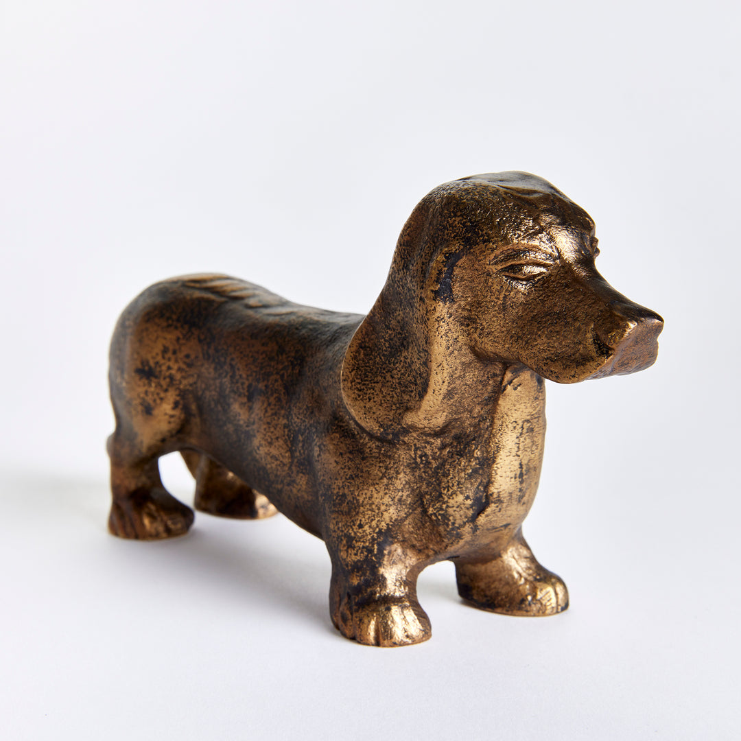 Angled close view of Baxter dachshund sculpture showing its modeled face, drooping ears and antique brass finish. Eclectic
