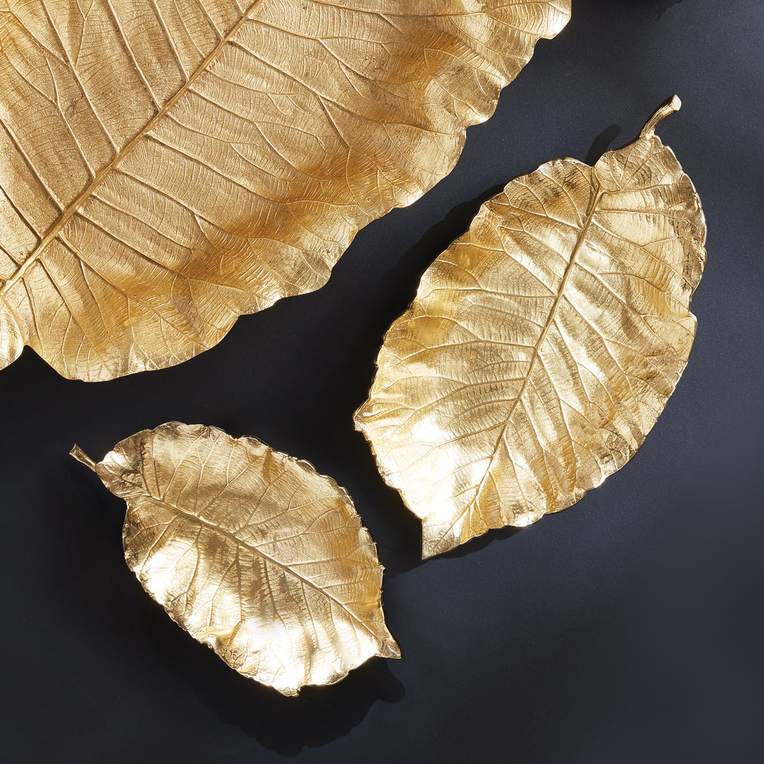 Each tray is carefully hand-carved using a clay mold to preserve the intricate leaf details. Constructed from aluminum, these trays are sturdy and adorned with a beautiful golden hue. Whether placed on a coffee table, console, or countertop, they are guaranteed to be the focal point.