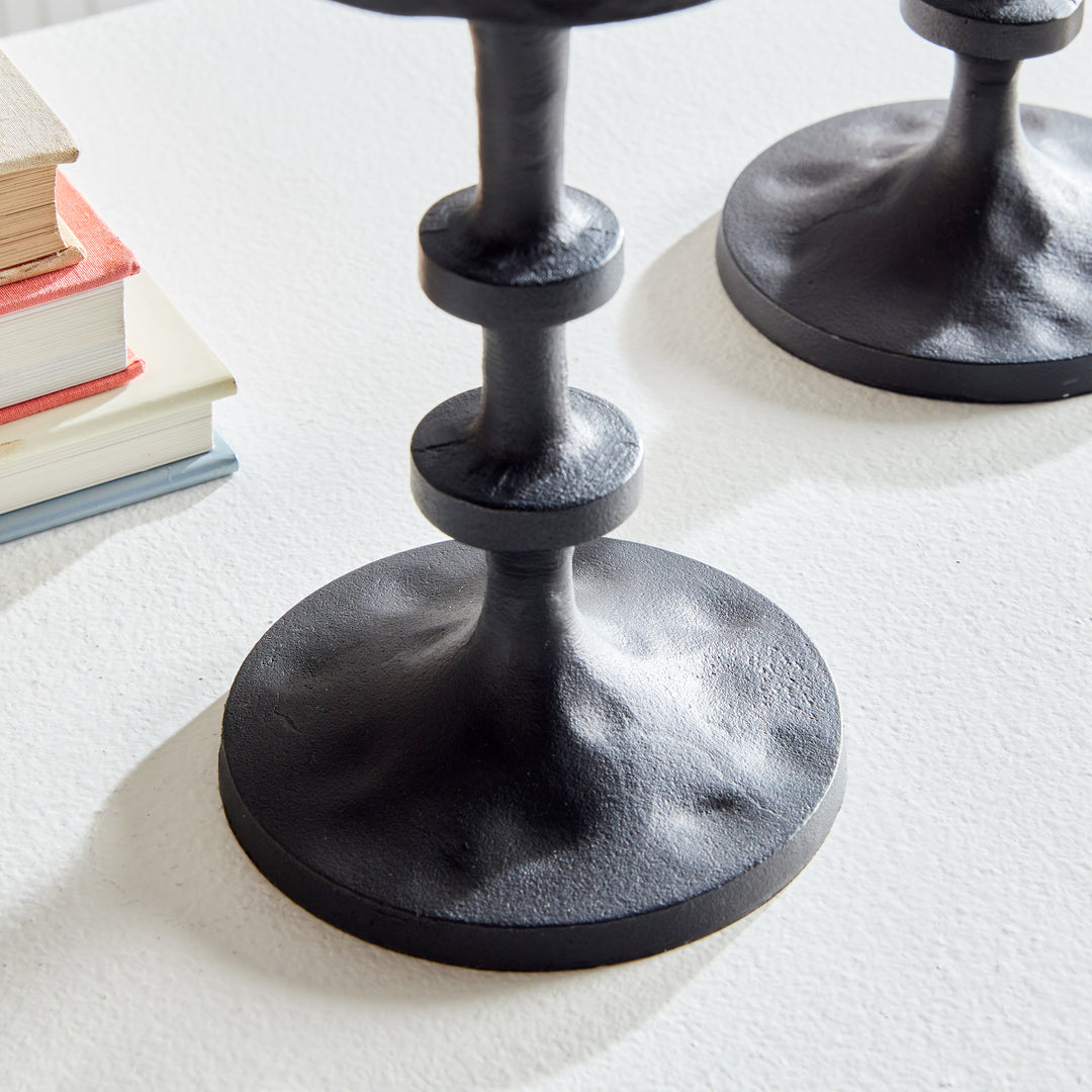 Front view of black aluminum pillar candle holders with elevated sculptural stacked silhouette – Transitional