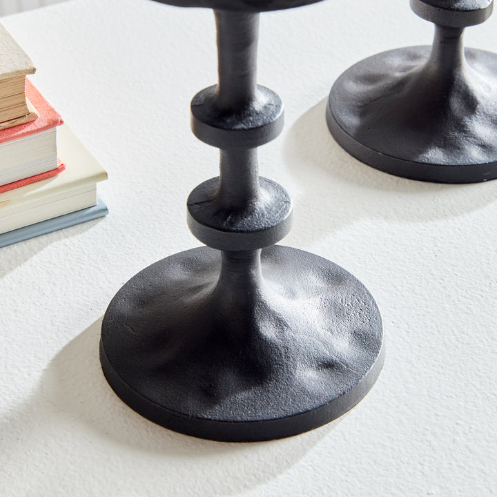 Front view of black aluminum pillar candle holders with elevated sculptural stacked silhouette – Transitional