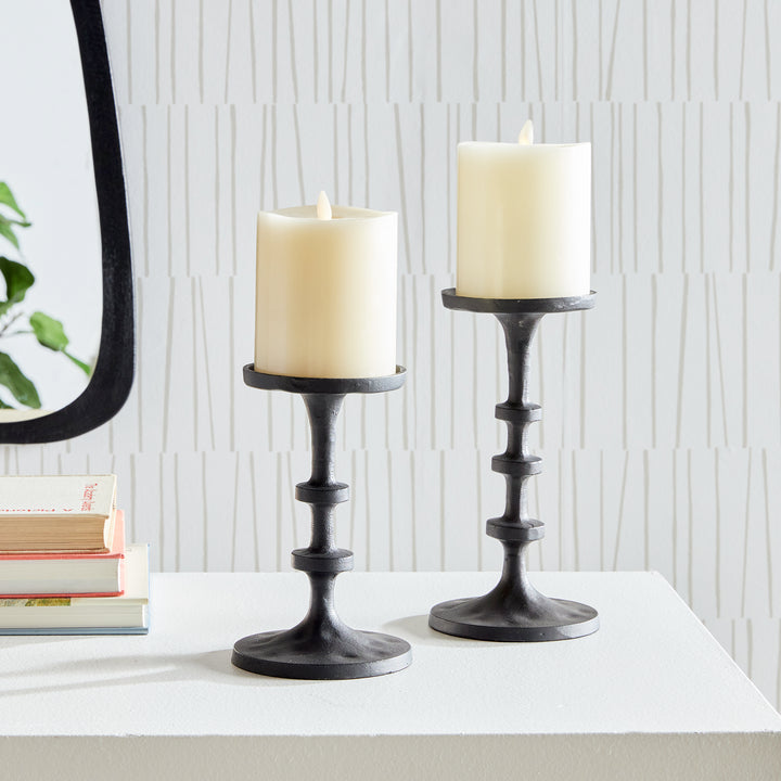 Sculptural black aluminum pillar candle holders displayed on a marble tabletop surface – Transitional