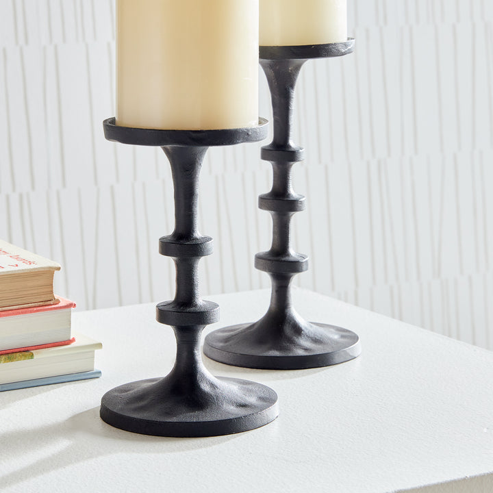 Black aluminum candle holders styled on shelving with books and layered decorative accents – Transitional