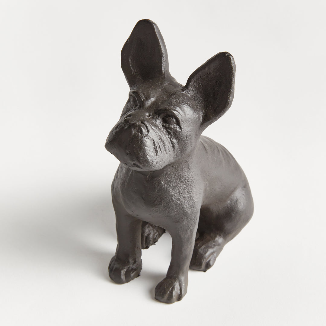 Close-up of dog figurine from the front, highlighting cast aluminum texture and alert expression in a sculptural seated pose.