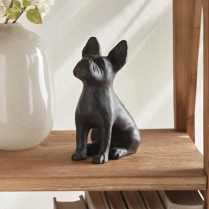 Sculpted dog figurine seated beside ceramic vase on shelf, shown in natural daylight to highlight size and decorative scale.