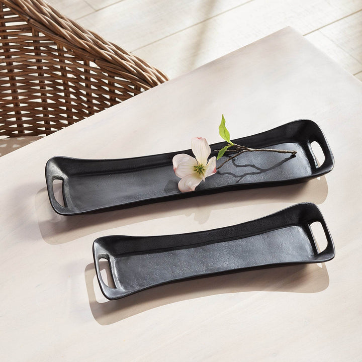 Black metal trays styled with a single flower on a pale surface – Urban Contemporary.

