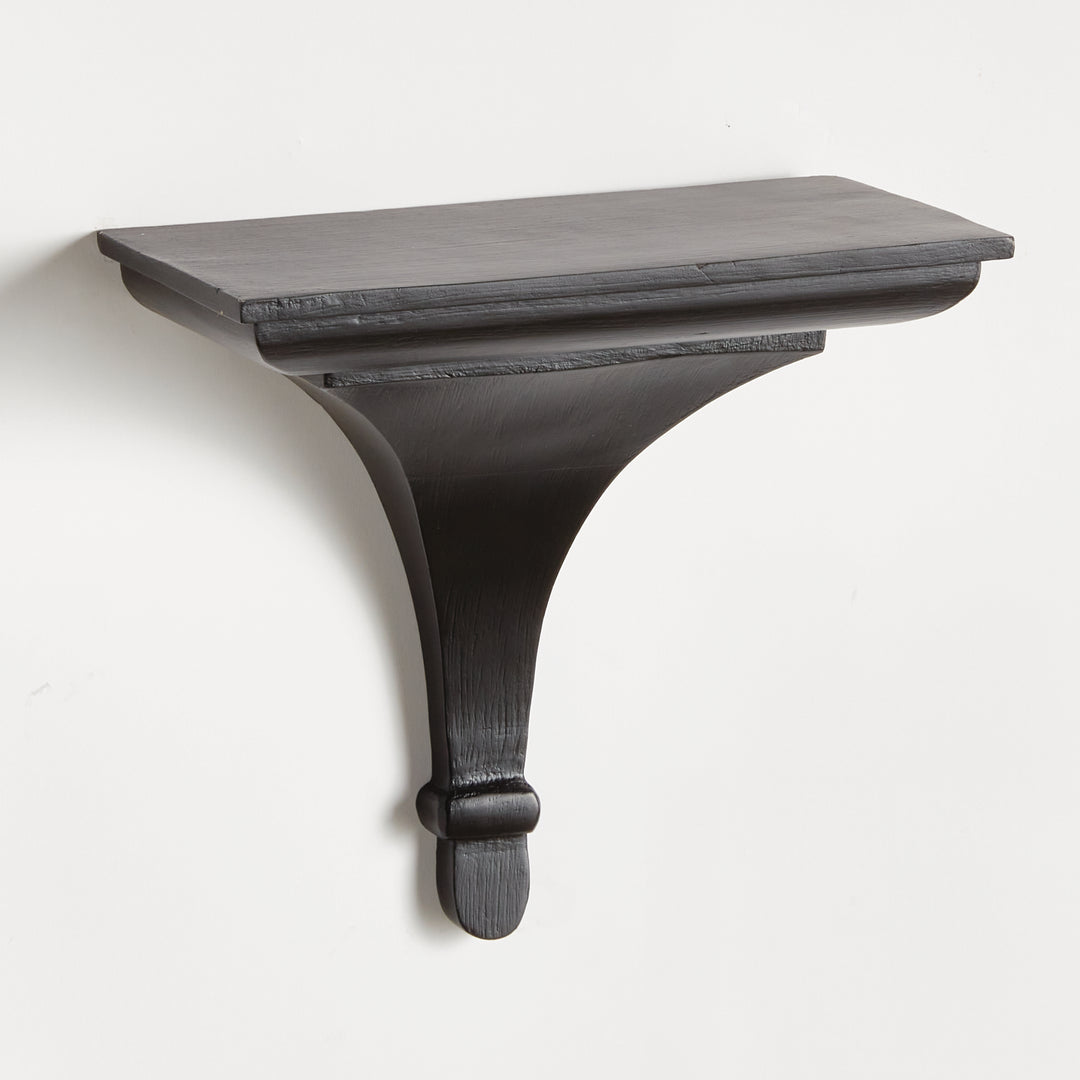 Black wood decorative wall bracket shelf with curved corbel design, mounted on wall and shown from the front in sharp detail.