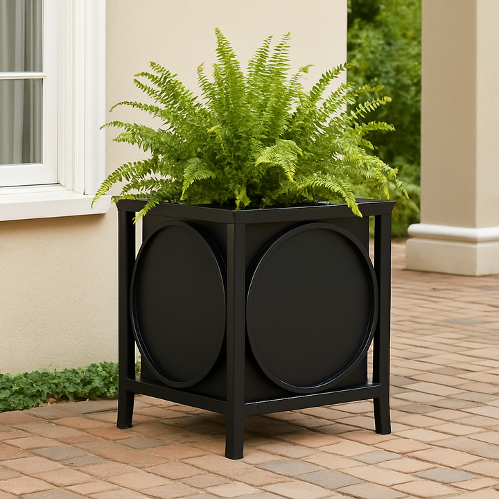 Black iron planter with Boston fern on a herringbone brick patio beside a stucco wall, styled for transitional outdoor elegance.