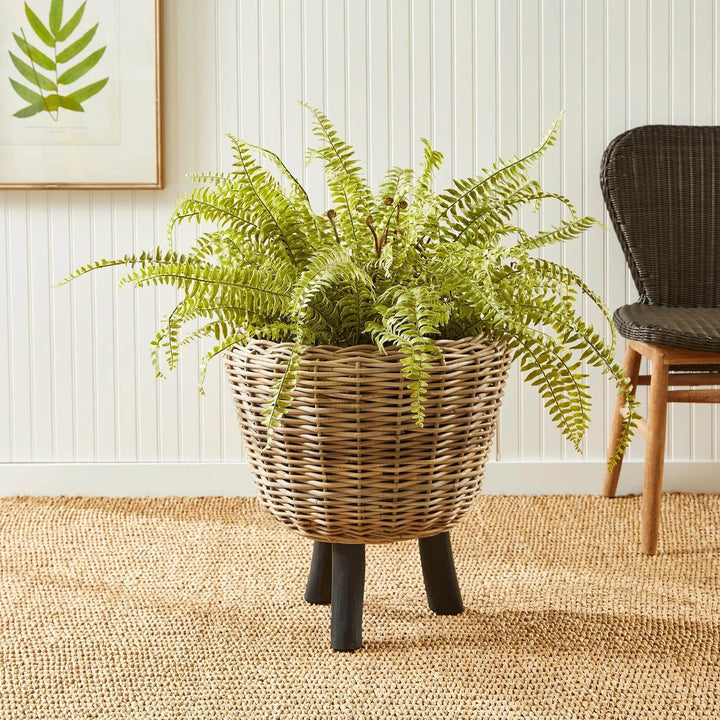 Natural rattan planter with black legs styled with fern on woven rug, ideal for indoor boho decor
