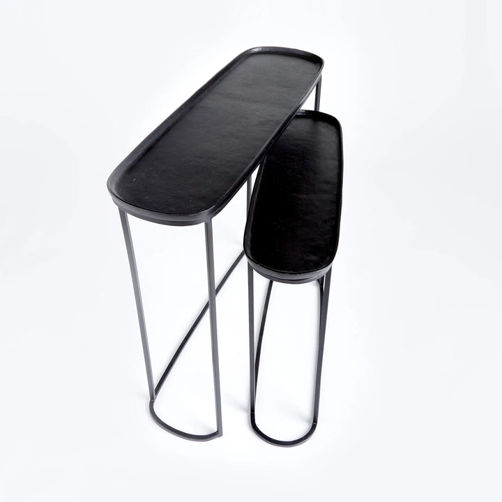 Black metal nesting console tables set of 2 shown at angle highlighting tray tops and slim open frame structure