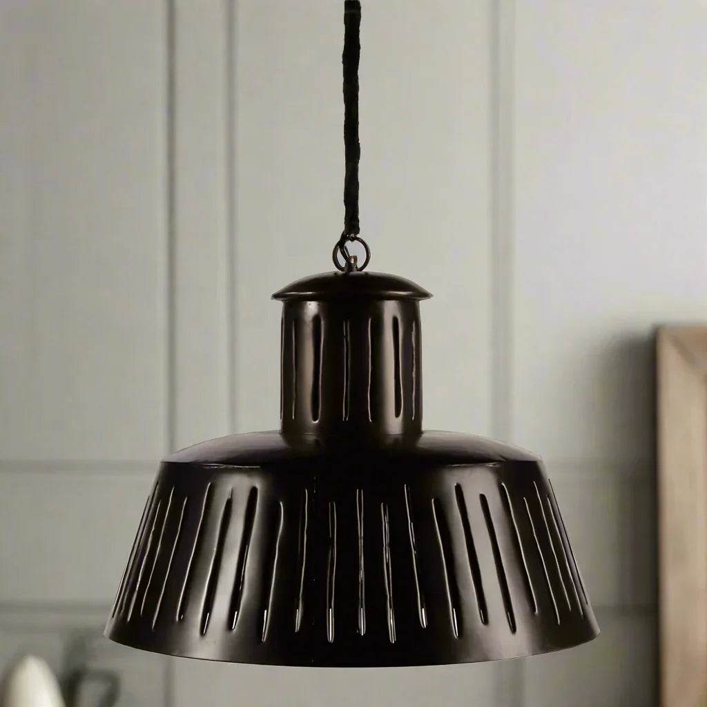 Black metal pendant light with slotted shade hanging in kitchen or dining space – Modern Industrial.
