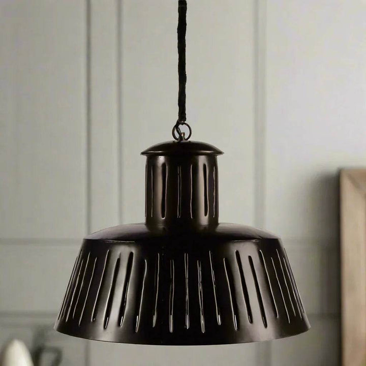 Black metal pendant light with slotted shade hanging in kitchen or dining space – Modern Industrial.
