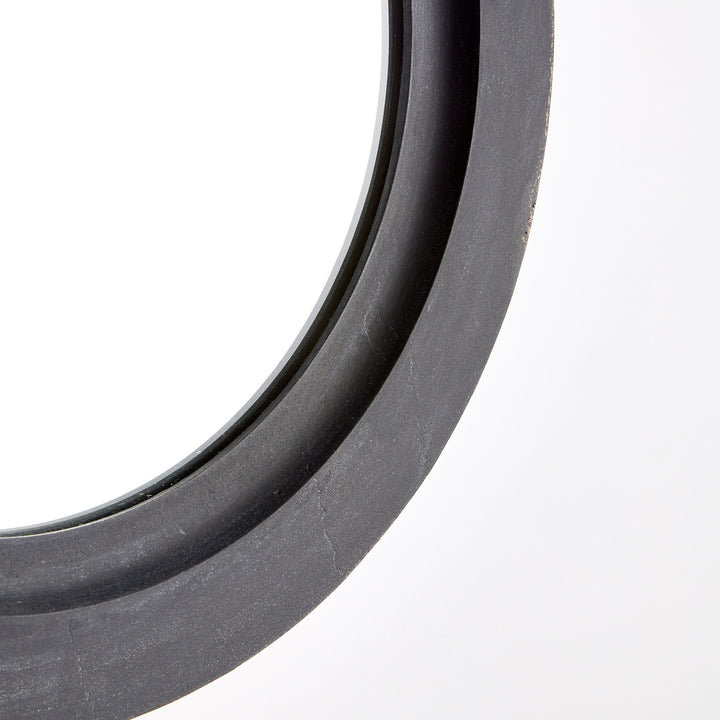 Macro detail of black round mirror frame texture showing smooth matte finish and clean molded edge.

