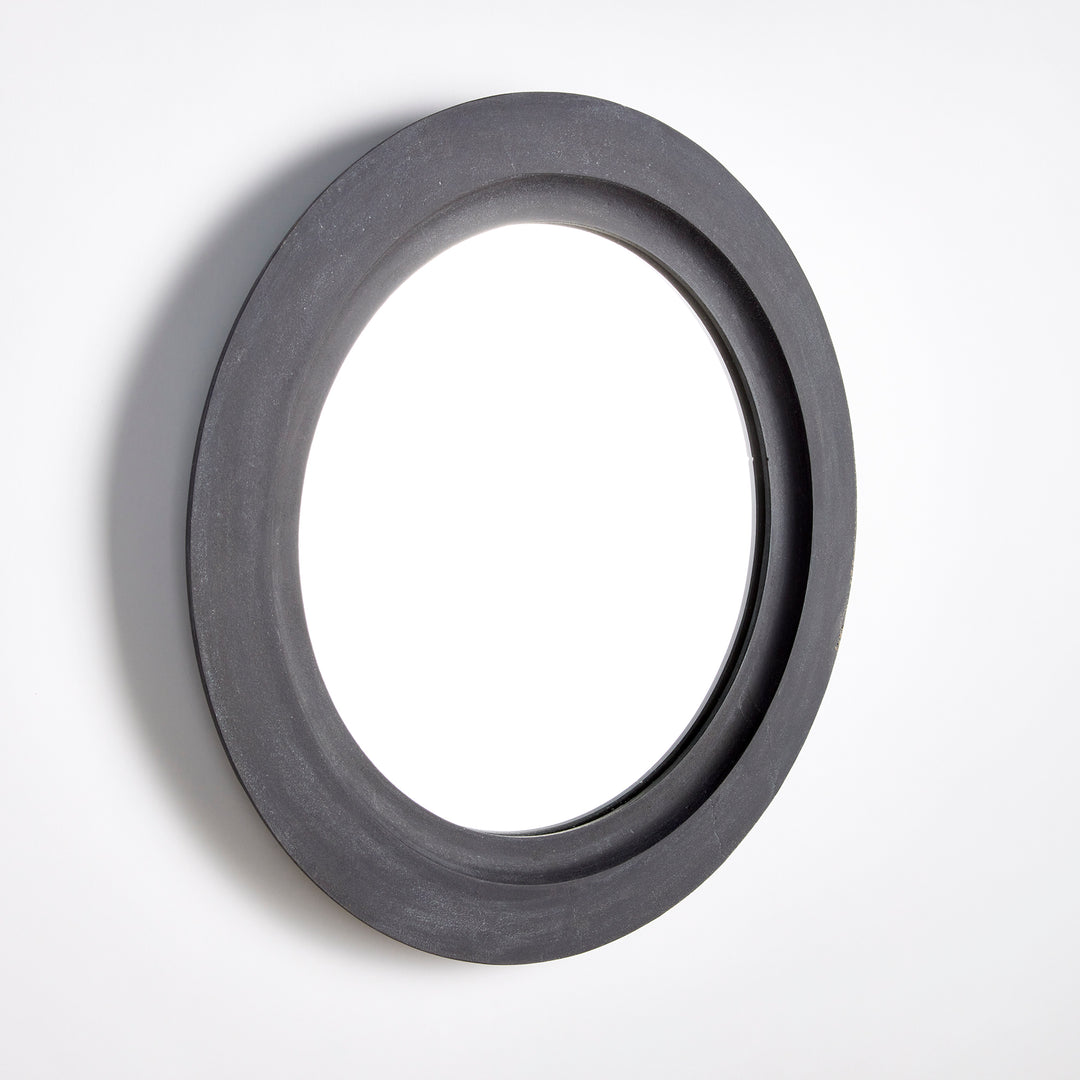 Studio image of black round wall mirror photographed at side angle to show depth and sculptural contour of frame.

