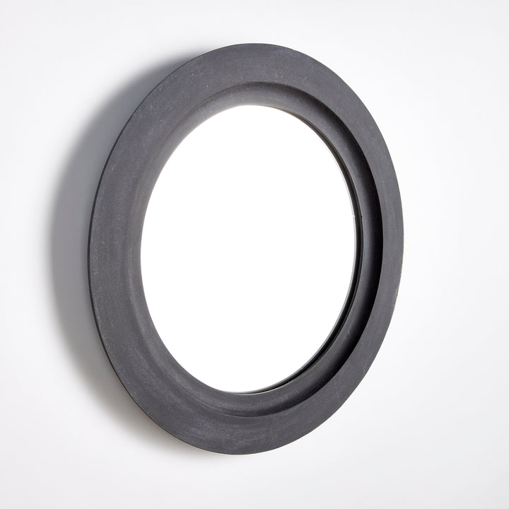 Studio image of black round wall mirror photographed at side angle to show depth and sculptural contour of frame.

