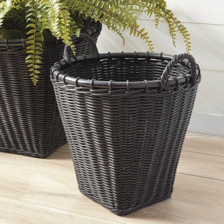 Single black rattan basket, three-quarter angle; tapered sides, wrapped handles, black weave on wood floor – Modern Boho.