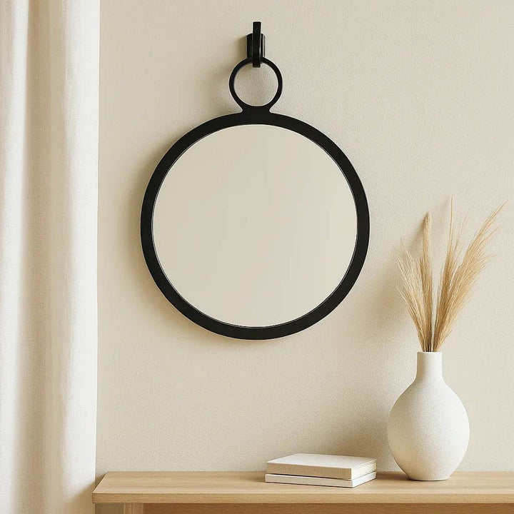 Black round wall mirror in modern coastal entryway, styled with driftwood console and soft neutral textures