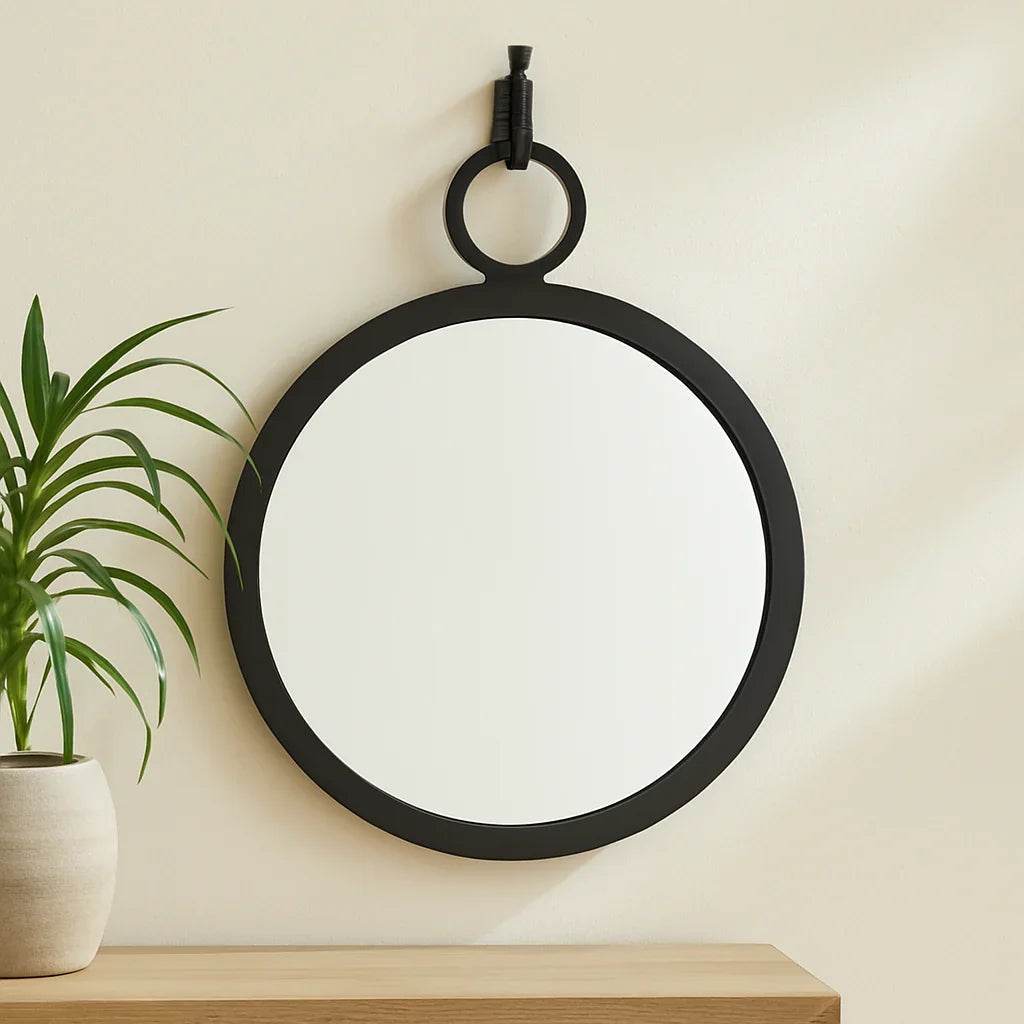 Minimalist bedroom with black round wall mirror and coastal-inspired neutral decor on soft white wall