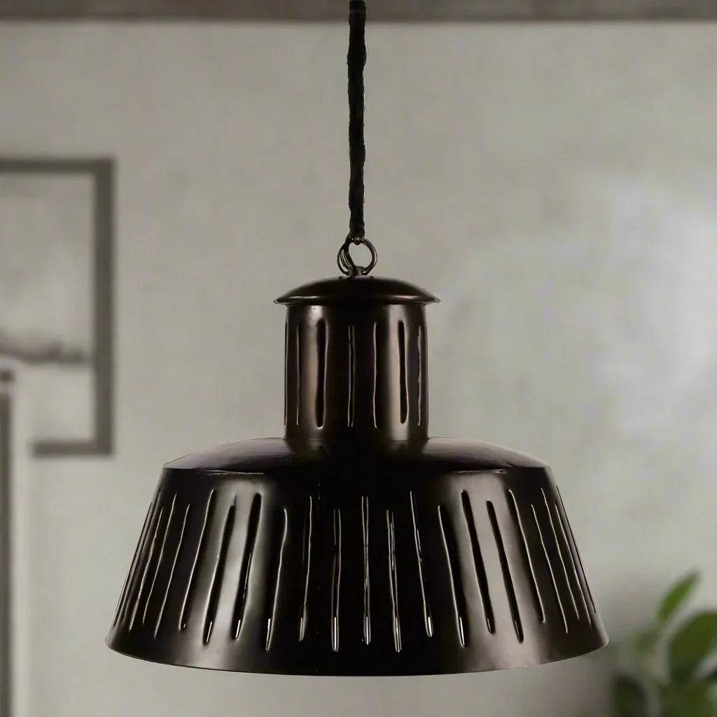 Black slotted metal pendant light hanging in dining room with modern industrial decor.