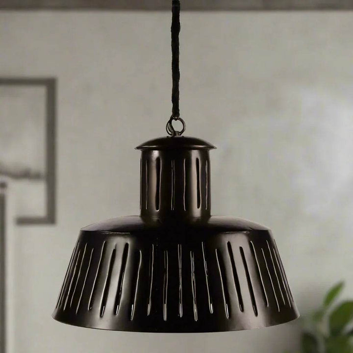 Black slotted metal pendant light hanging in dining room with modern industrial decor.
