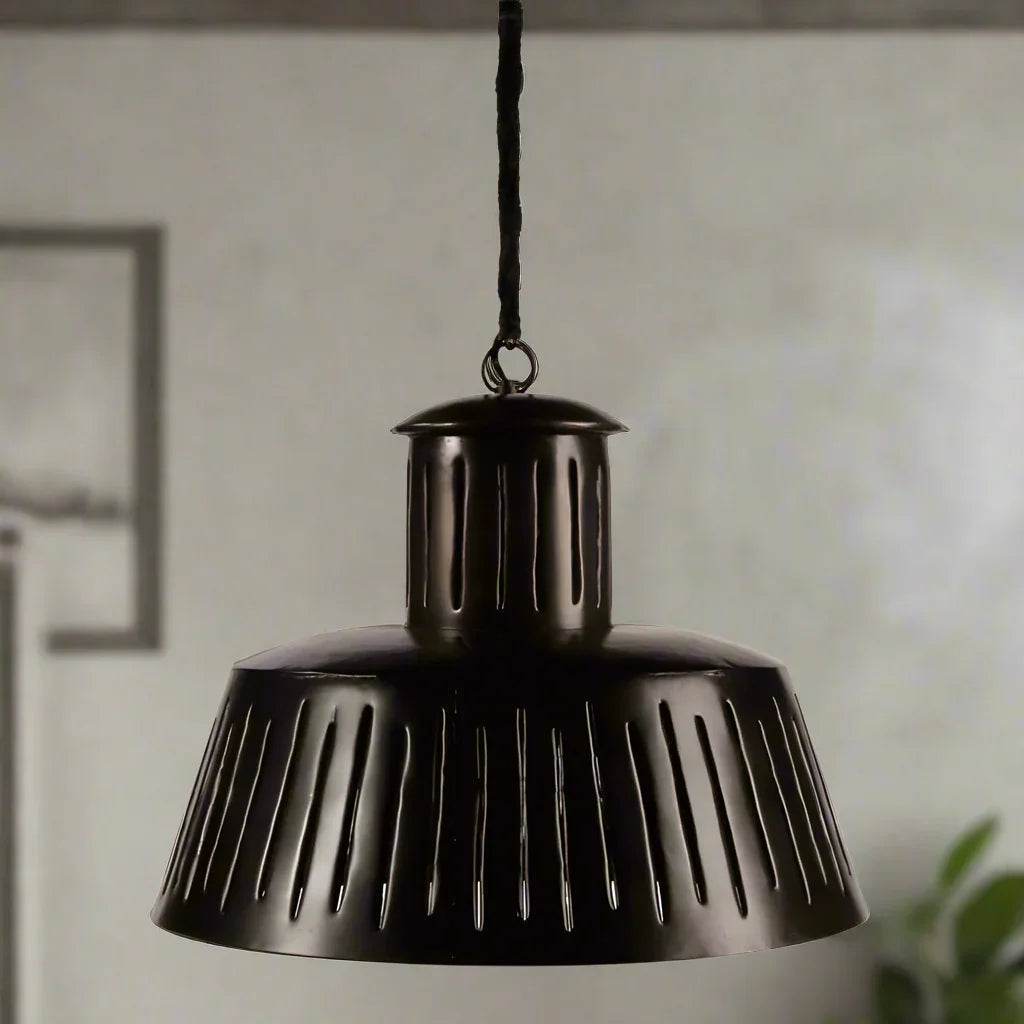 Black slotted metal pendant light hanging in dining room with modern industrial decor.