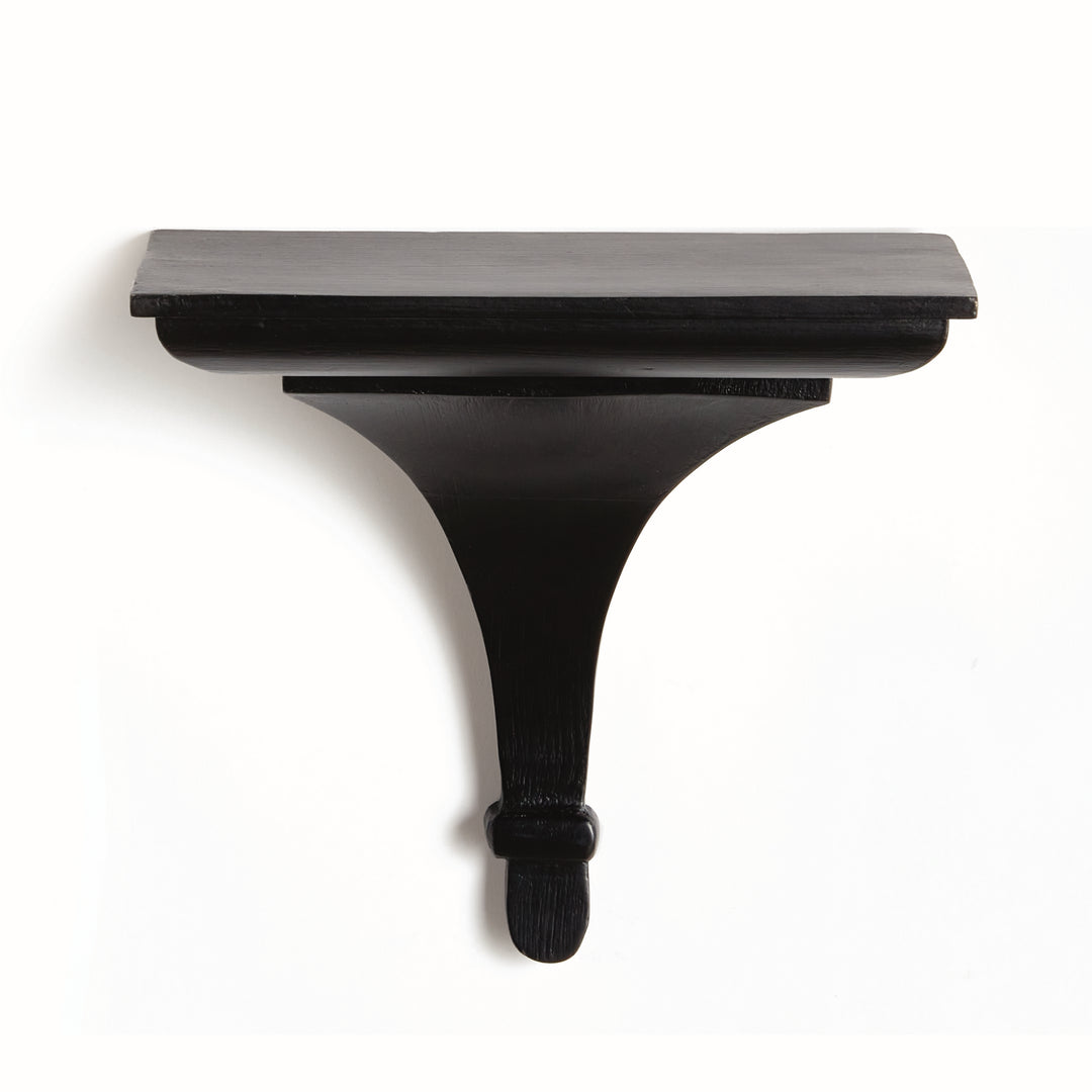 Matte black wood decorative bracket shelf on light textured plaster wall, styled with soft shadows and architectural contrast.