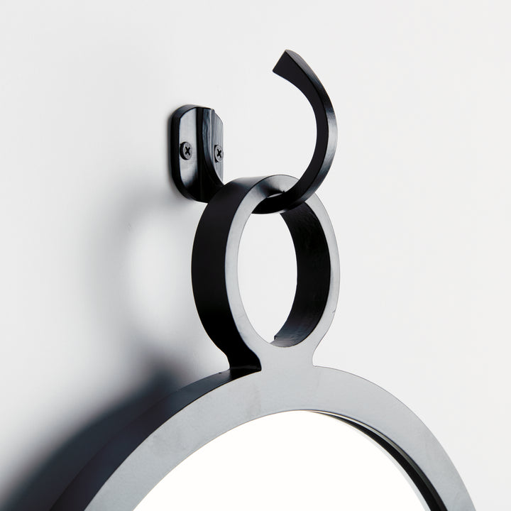 Close-up of sculptural black hook on modern round mirror, matte finish for Scandinavian minimal décor