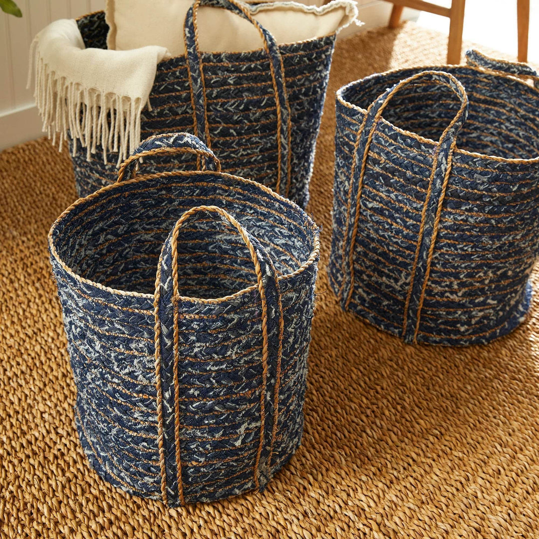 Trio of denim and seagrass woven baskets placed on a neutral jute area rug