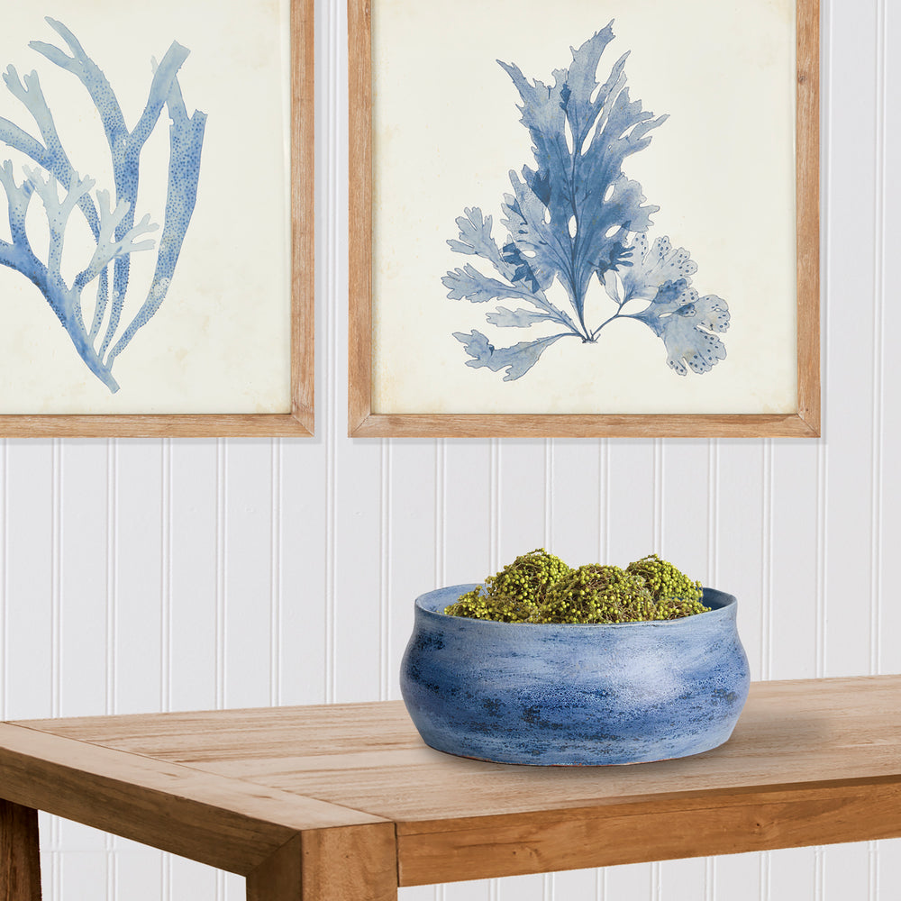 Blue ceramic decorative bowl on wood table with artwork in background, perfect for layering in entryway or living room – Coastal Transitional.

