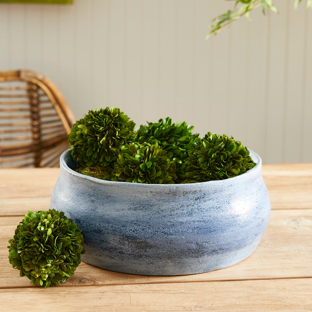 Blue ceramic decorative bowl styled with moss balls on wood table, ideal for coffee table or console styling – Coastal Transitional.