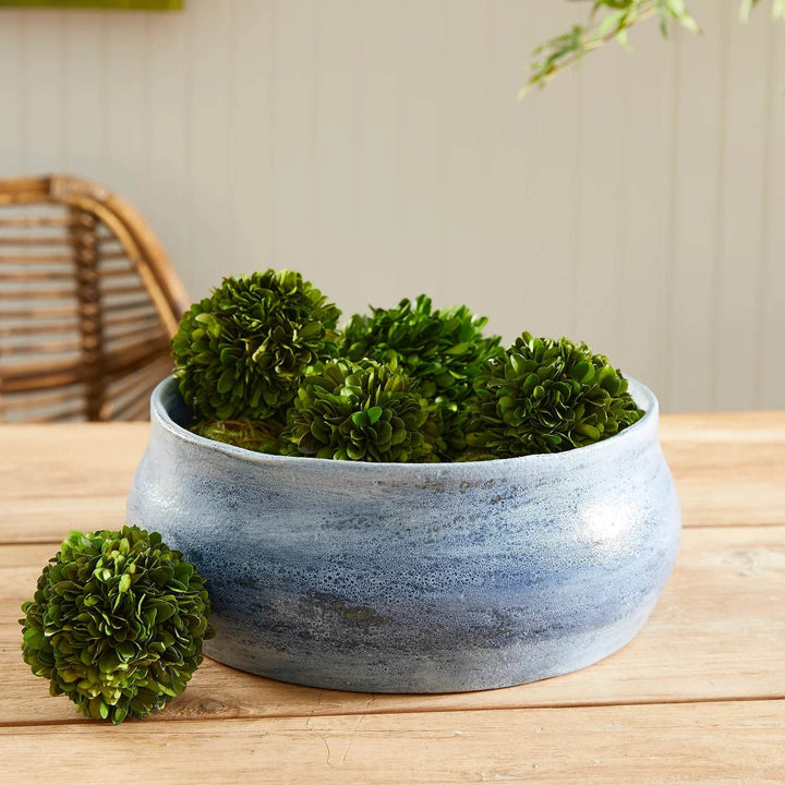 Blue ceramic decorative bowl styled with moss balls on wood table, ideal for coffee table or console styling – Coastal Transitional.