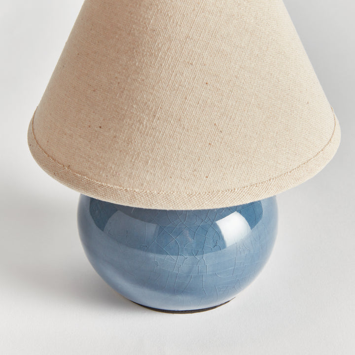 Blue ceramic mini table lamp close-up showing crackle glaze and the lower edge of its linen shade - Coastal Transitional