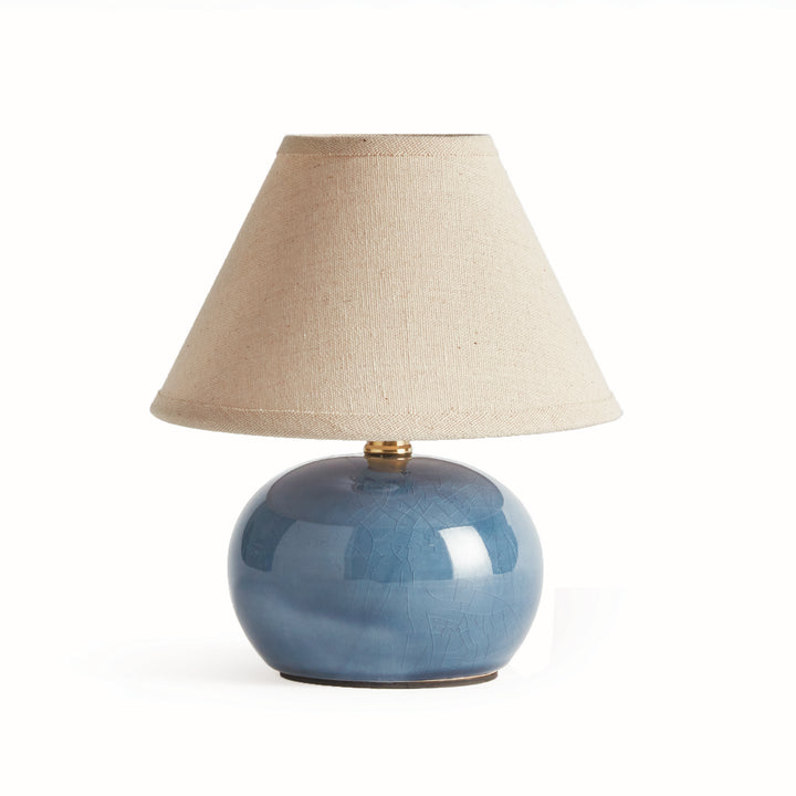 Blue ceramic mini table lamp with a rounded glazed base and tapered cream linen shade on plain white - Coastal Transitional
