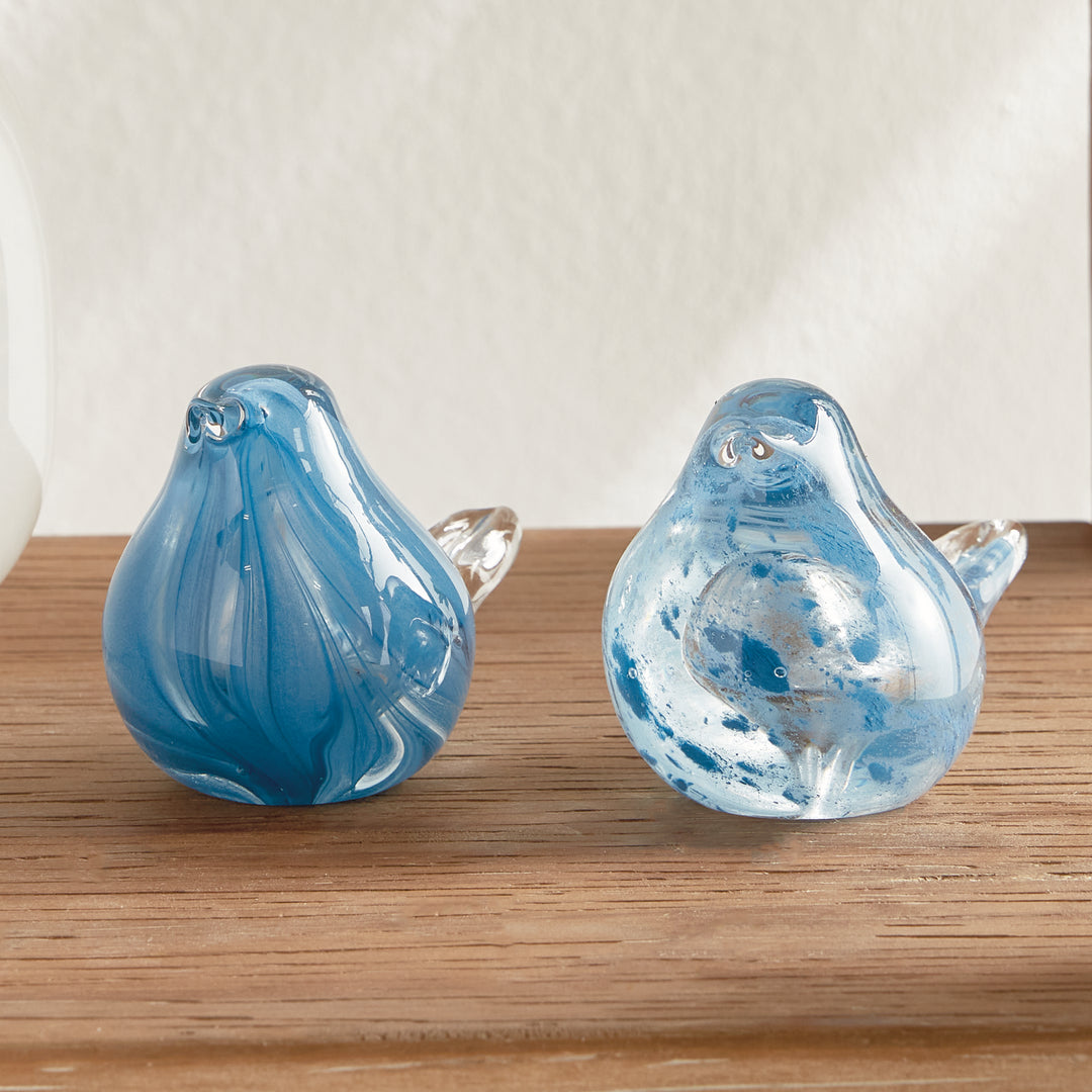 Set of two hand blown blue glass finch sculptures displayed on wood tabletop, decorative bird accents for shelves or tables.