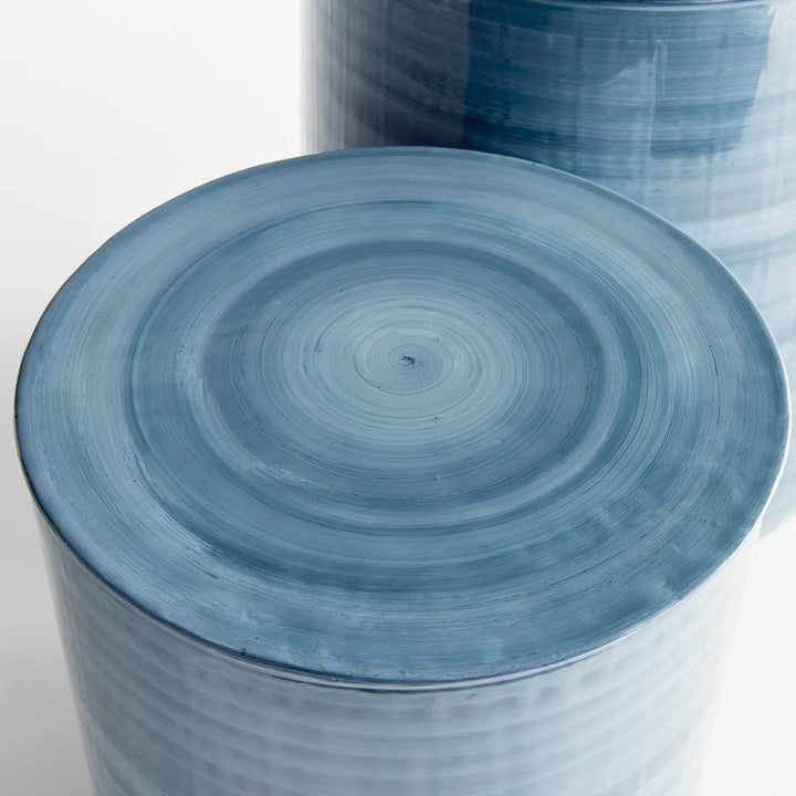 Close-up of removable round lid from iron storage table, showing hand-painted circular swirl in blue gray enamel – Coastal