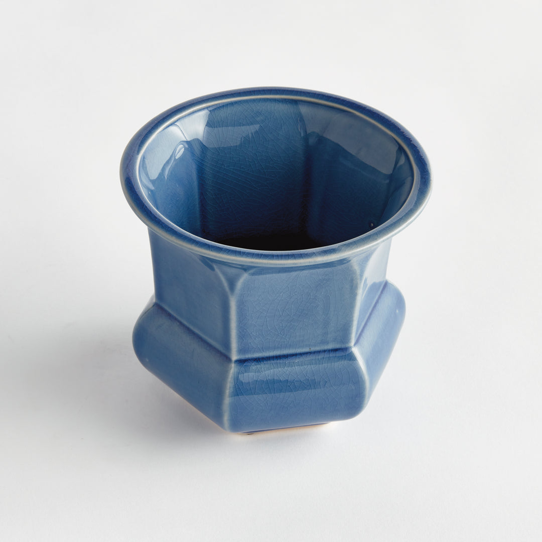 Angled view of a blue reactive glaze ceramic planter showing its flared rim and faceted sides against white, Traditional