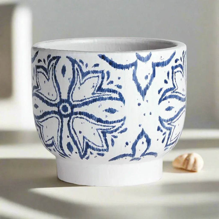 Blue and white ceramic cachepot planter shown in soft daylight with floral medallion pattern and pedestal base – Coastal Casual.

