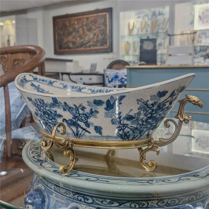 Blue and white porcelain decorative bowl with bronze ormolu base on glass table in traditional interior