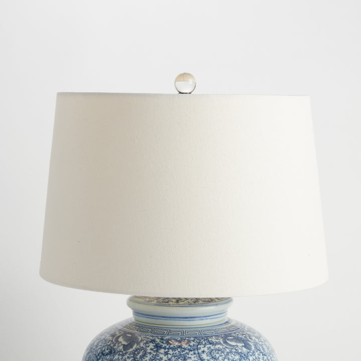 Angled view of blue and white porcelain lamp showing linen shade and flared base silhouette – Transitional style.