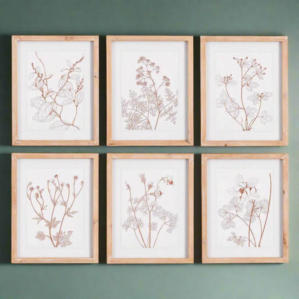 Blush botanical prints styled as a grid set on a muted green gallery wall
